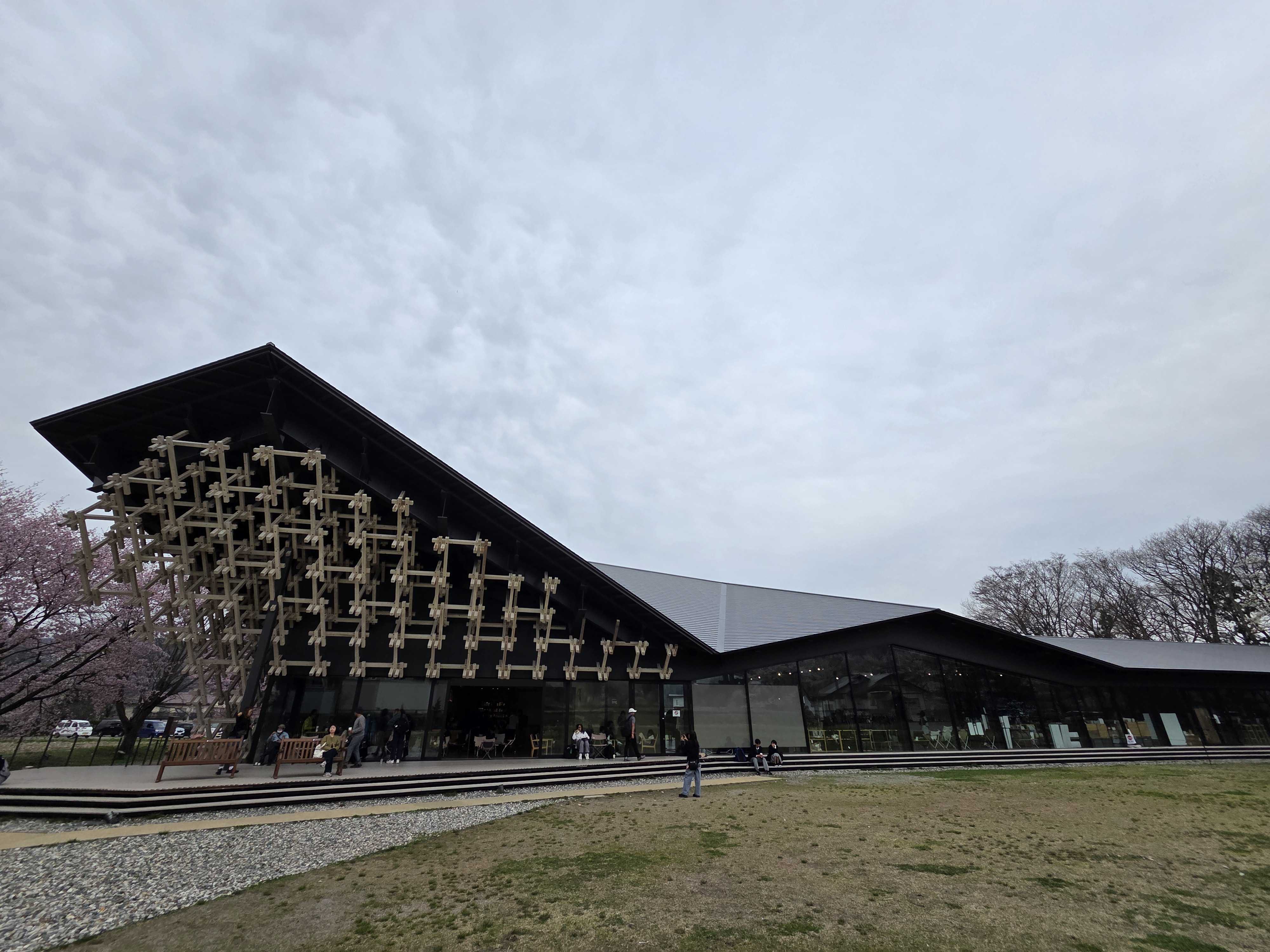 Snow Peak Land Station Hakuba designed by Kengo Kuma with wooden lattice facade and cherry blossoms